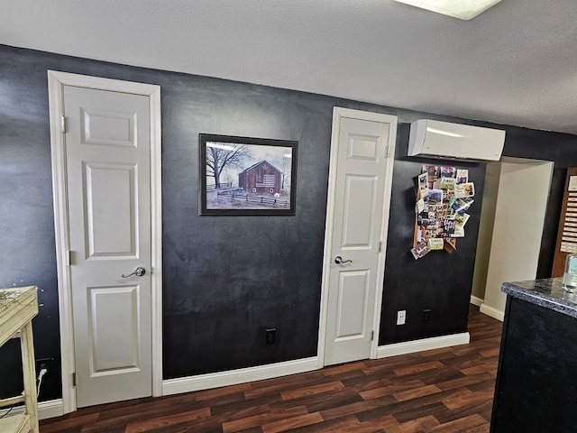 kitchen with baseboards, dark wood-style flooring, and an AC wall unit