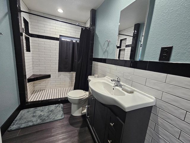 full bath with a shower stall, a textured wall, toilet, and vanity