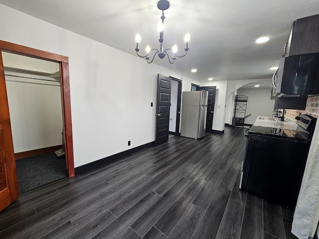 kitchen with a notable chandelier, a sink, stainless steel appliances, arched walkways, and dark wood-style flooring