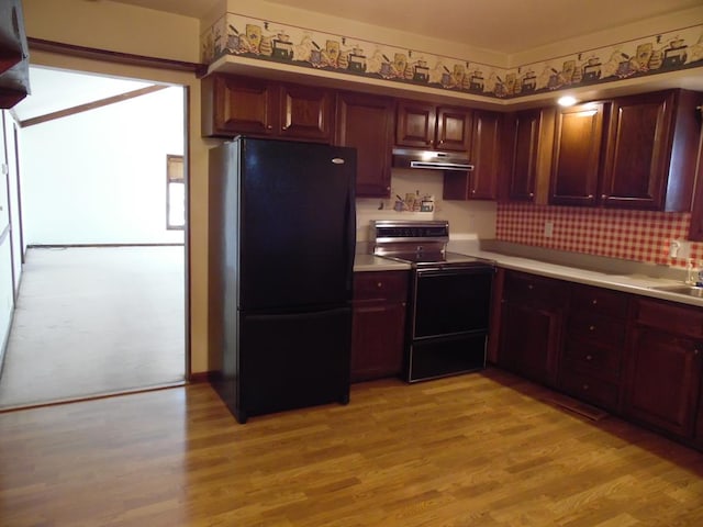 kitchen with electric range, light hardwood / wood-style flooring, black fridge, and sink