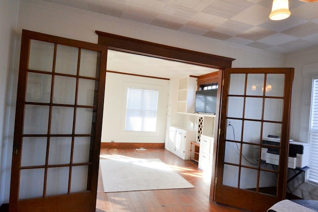 unfurnished bedroom with french doors, ornamental molding, and hardwood / wood-style flooring