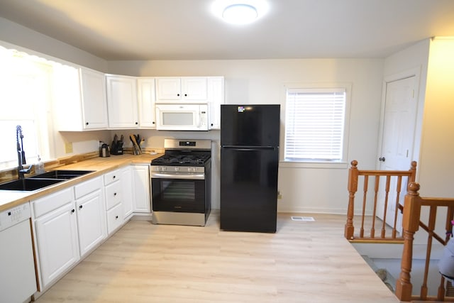 kitchen featuring light countertops, visible vents, white cabinetry, a sink, and white appliances