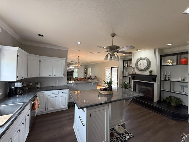 kitchen featuring dishwashing machine, a glass covered fireplace, white cabinets, dark wood-style flooring, and open floor plan