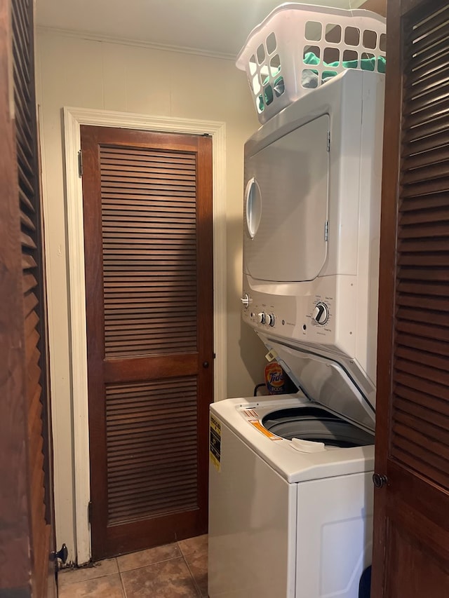 laundry room with tile patterned flooring, crown molding, and stacked washer / dryer