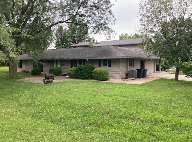 back of property featuring a garage, a yard, and central air condition unit