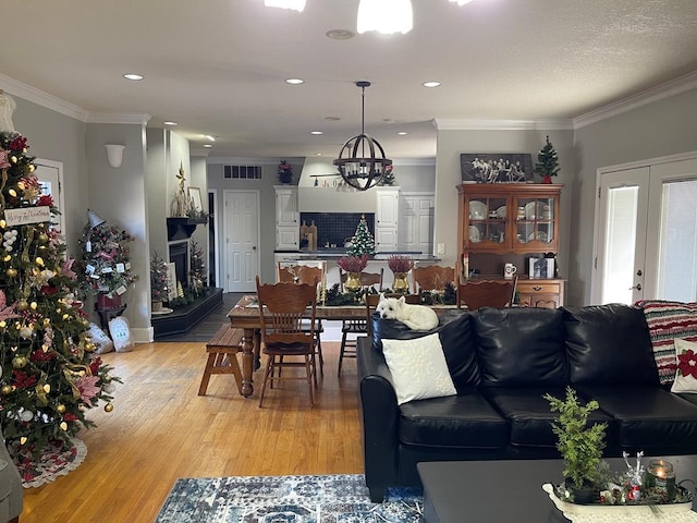 living room with french doors, light hardwood / wood-style flooring, a notable chandelier, and ornamental molding