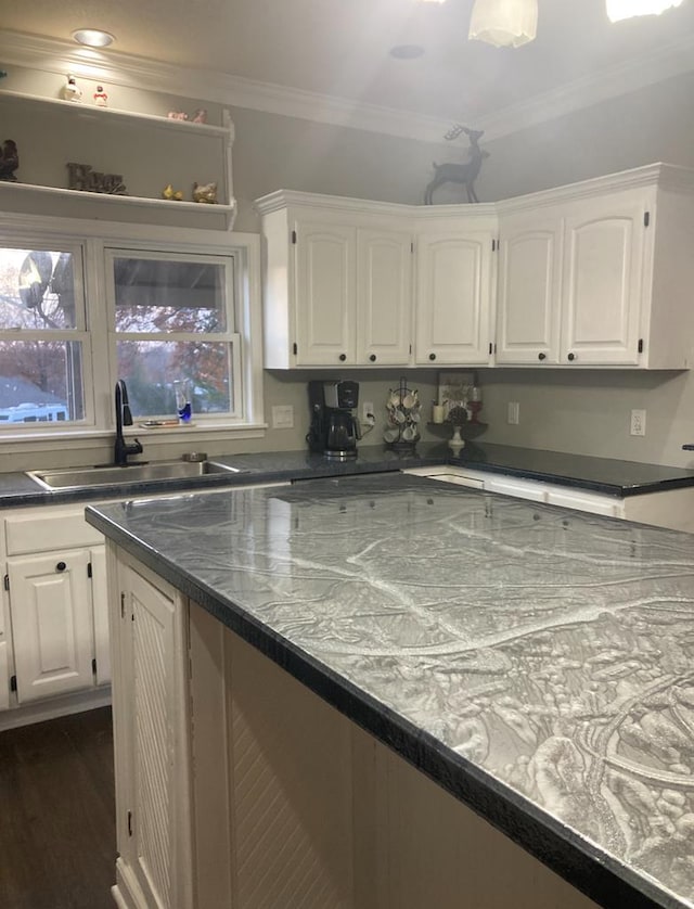 kitchen with dark wood-type flooring, white cabinetry, crown molding, and sink