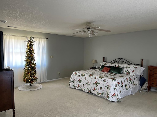 bedroom featuring a textured ceiling, light colored carpet, and ceiling fan