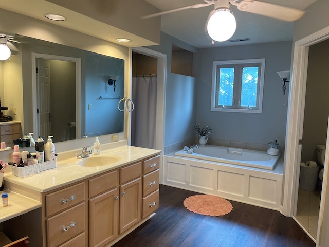 bathroom with a bathing tub, ceiling fan, hardwood / wood-style floors, toilet, and vanity