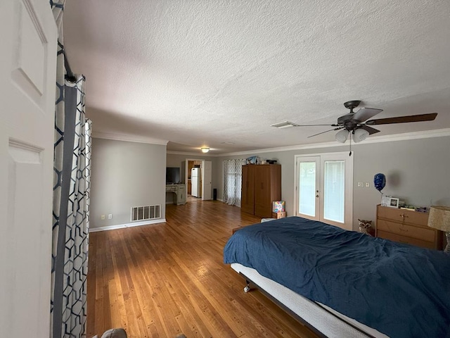 bedroom with ornamental molding, visible vents, wood finished floors, and a textured ceiling