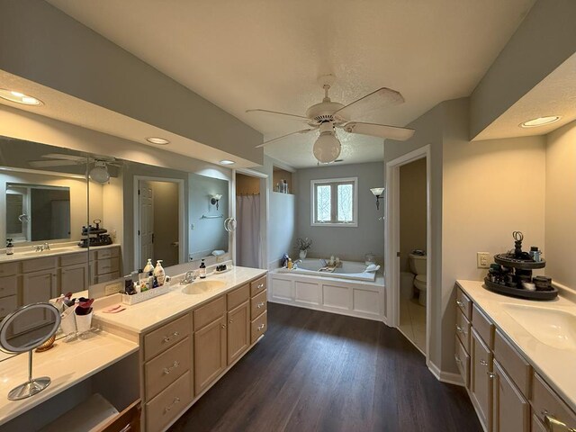 full bathroom featuring toilet, wood finished floors, a sink, and a ceiling fan
