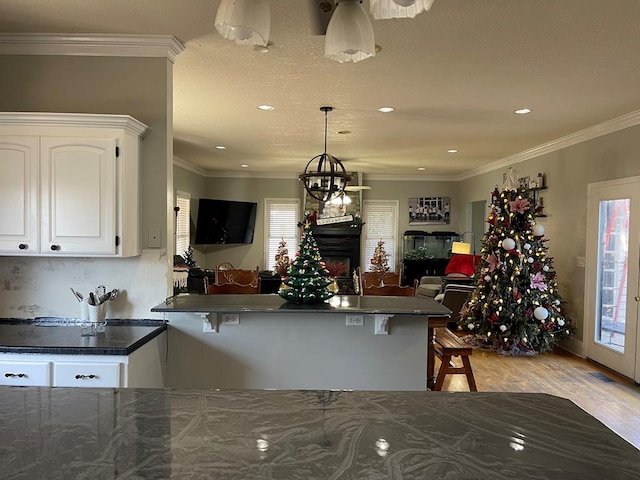 kitchen featuring white cabinetry, kitchen peninsula, pendant lighting, a breakfast bar, and ornamental molding