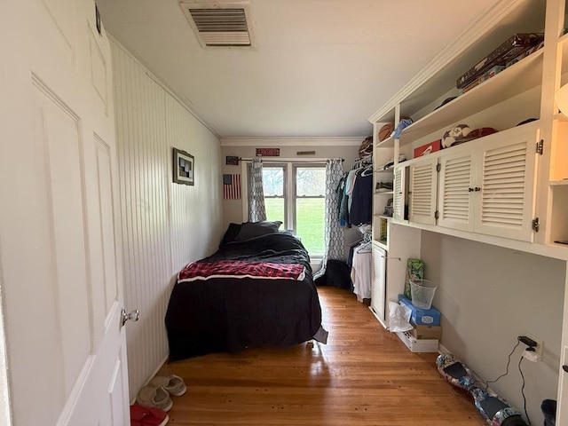 bedroom with crown molding, visible vents, and light wood-type flooring