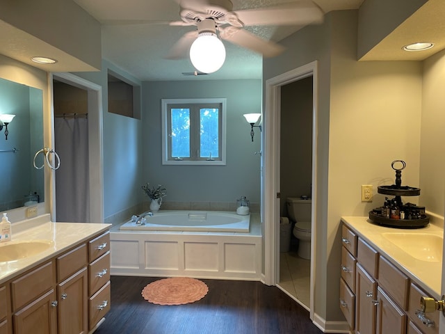 bathroom with hardwood / wood-style flooring, a washtub, vanity, and toilet