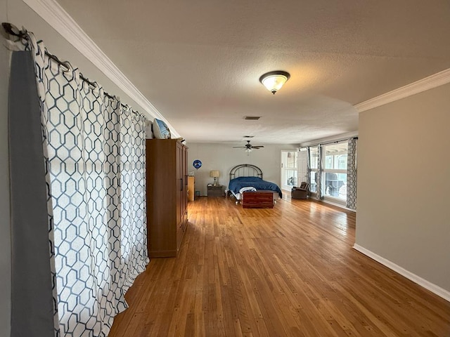 hallway with visible vents, baseboards, hardwood / wood-style floors, and crown molding