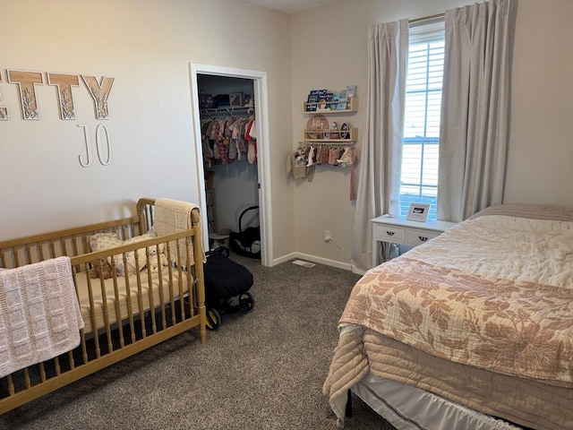 bedroom featuring a walk in closet, a closet, and dark colored carpet