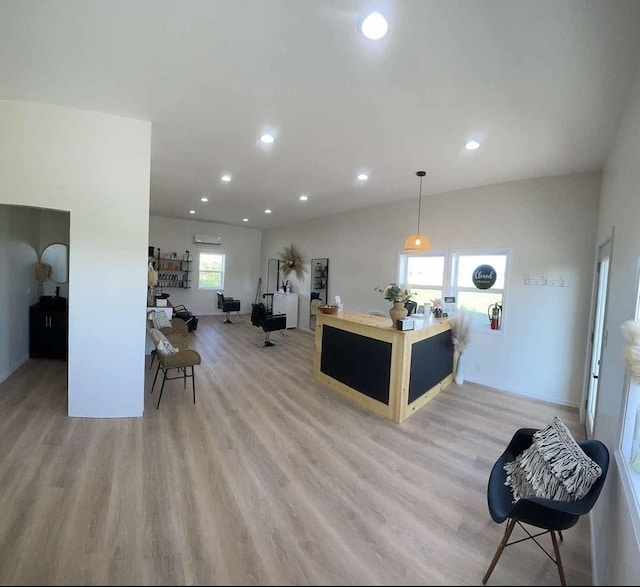 kitchen with a breakfast bar, decorative light fixtures, a wall mounted AC, and light hardwood / wood-style floors