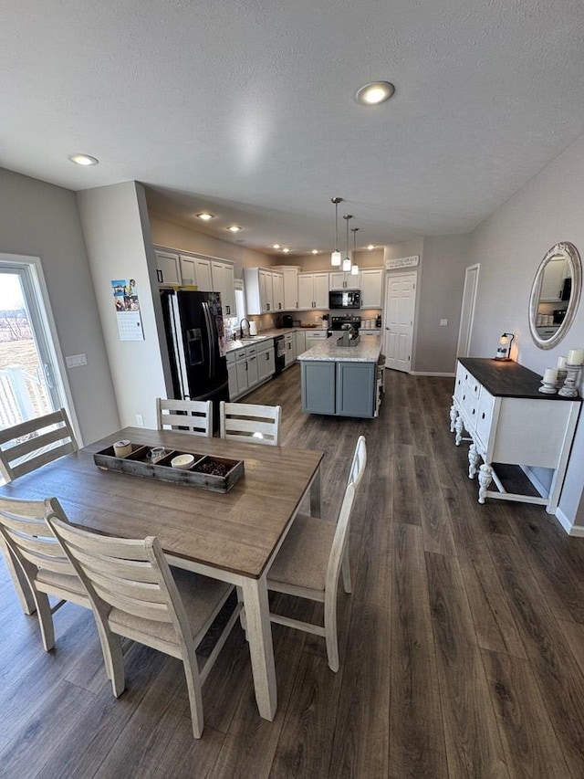 dining area featuring sink, dark wood-type flooring, and a textured ceiling