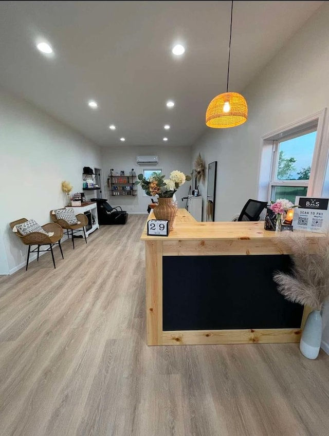 kitchen with wood counters, a wall mounted air conditioner, hanging light fixtures, and light hardwood / wood-style flooring