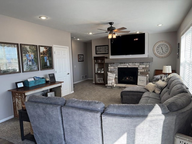 living room with a stone fireplace, carpet flooring, and ceiling fan