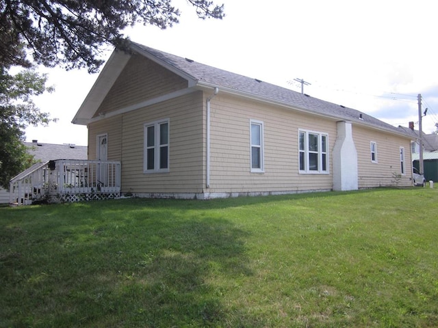 back of property with a wooden deck and a lawn