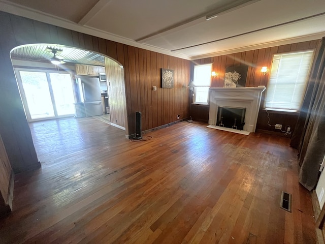 115 Polk St, Chillicothe, MO 64601 - unfurnished living room featuring crown molding, arched walkways, hardwood / wood-style floors, a fireplace, and wooden walls