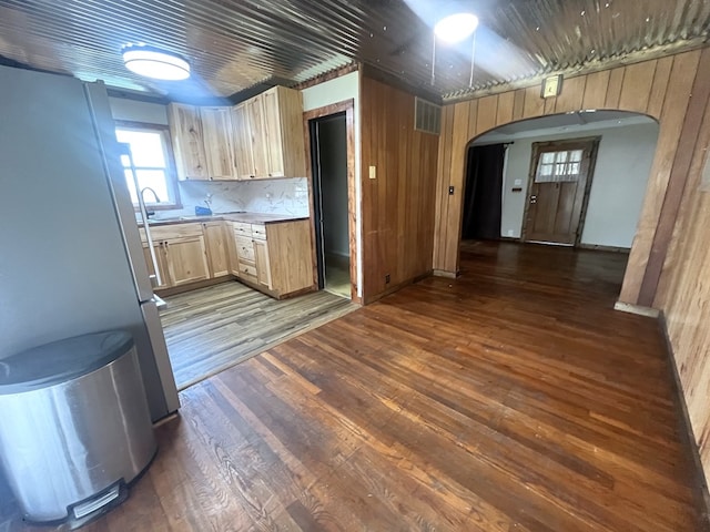 115 Polk St, Chillicothe, MO 64601 - kitchen featuring freestanding refrigerator, arched walkways, dark wood-style flooring, light countertops, and wooden walls