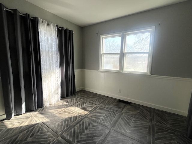 spare room with wainscoting and baseboards