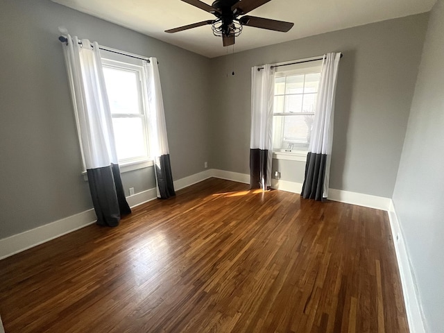 spare room featuring baseboards, ceiling fan, and dark wood-style flooring