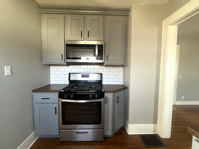 kitchen with dark wood finished floors, backsplash, gray cabinetry, and stainless steel appliances