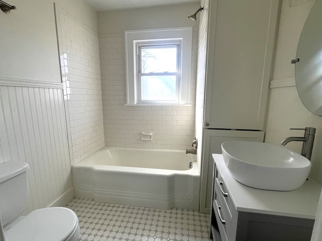 bathroom featuring tub / shower combination, toilet, wainscoting, and vanity