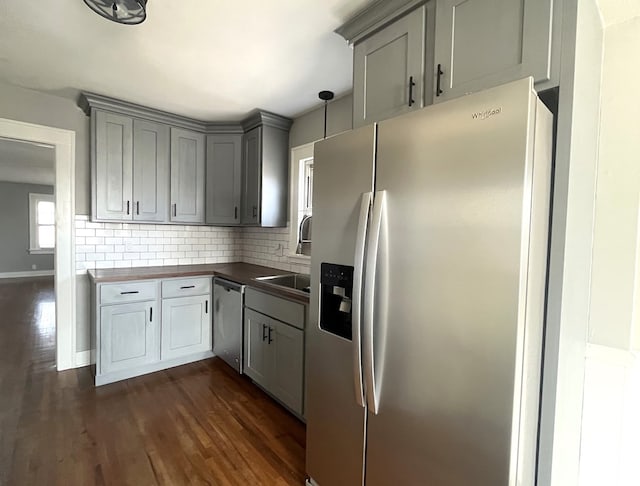 kitchen with fridge with ice dispenser, gray cabinetry, tasteful backsplash, stainless steel dishwasher, and dark wood finished floors