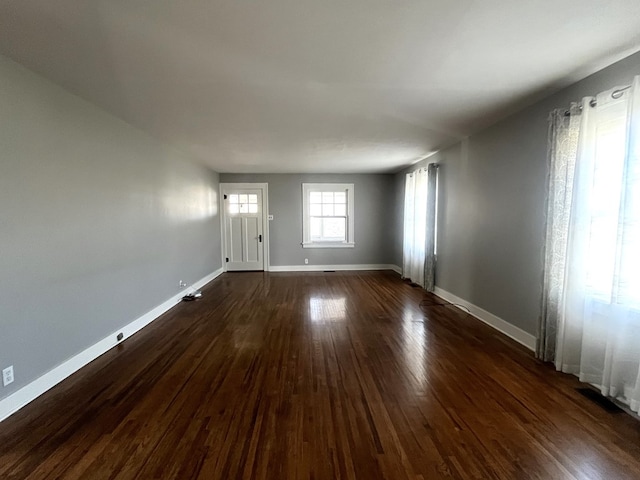 unfurnished living room with baseboards and dark wood-style flooring