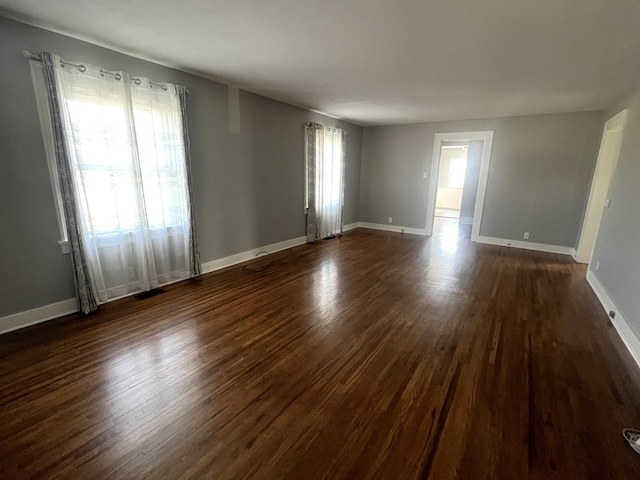 spare room featuring baseboards and dark wood-style flooring