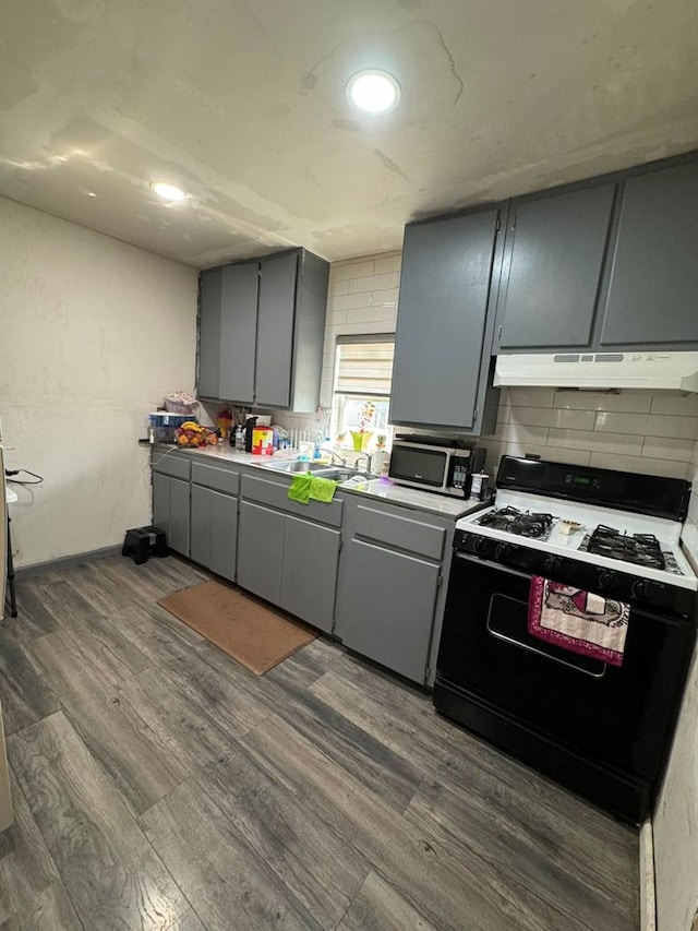 kitchen with black gas range, dark hardwood / wood-style floors, gray cabinetry, and sink