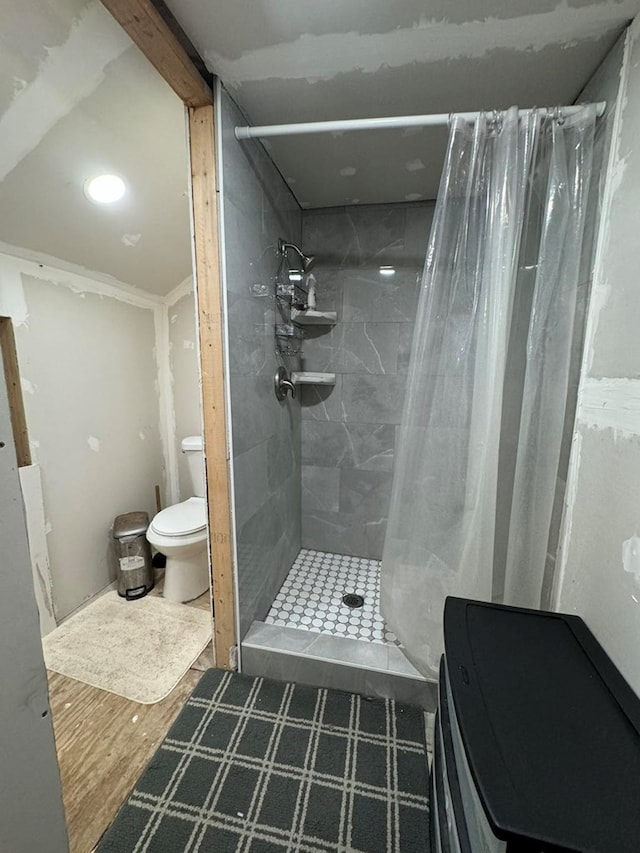 bathroom featuring curtained shower, wood-type flooring, and toilet