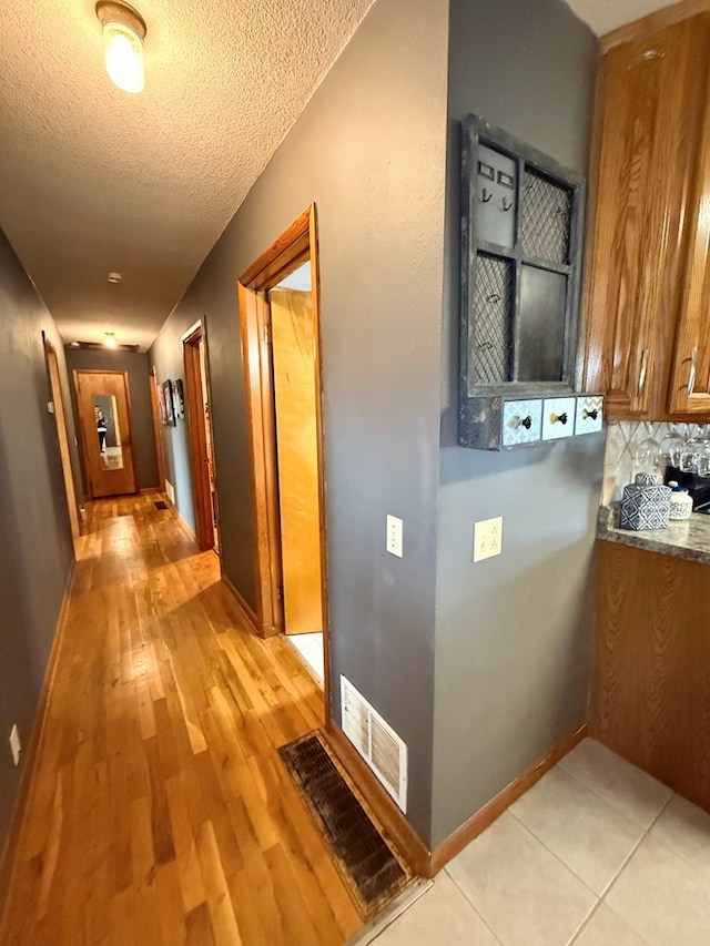 609 E Clark St, La Plata, MO 63549 - hall with a textured ceiling, light wood-style flooring, and baseboards