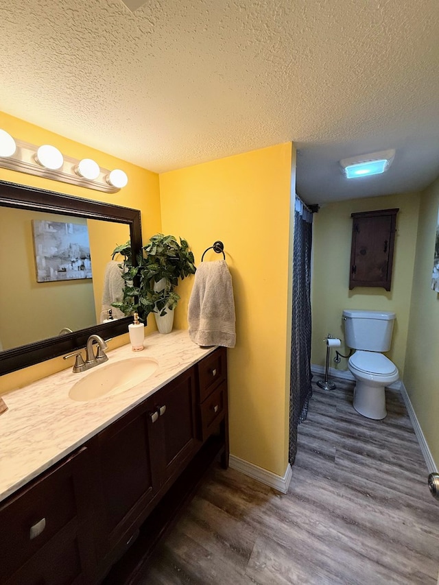 609 E Clark St, La Plata, MO 63549 - full bathroom with a textured ceiling, toilet, vanity, wood finished floors, and baseboards
