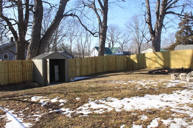 snowy yard with an outbuilding, a storage unit, and a fenced backyard