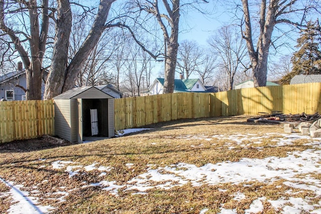 yard layered in snow with a storage unit, an outdoor structure, and a fenced backyard