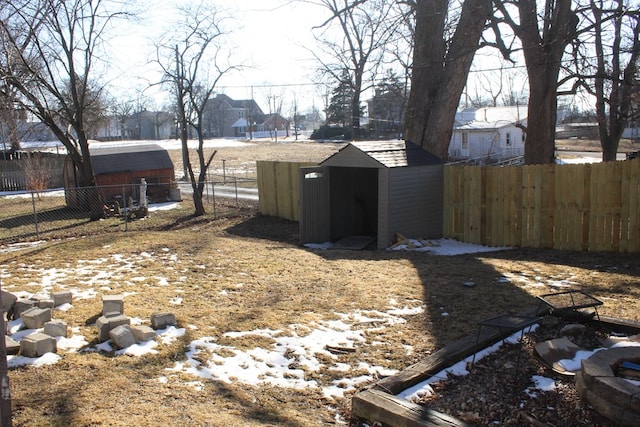 view of yard featuring an outbuilding, a fenced backyard, a residential view, and a storage shed