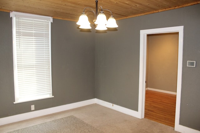 carpeted empty room with wooden ceiling, baseboards, and a notable chandelier