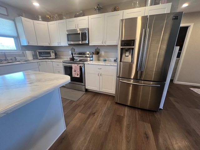 kitchen with a sink, white cabinetry, stainless steel appliances, a toaster, and dark wood-style flooring