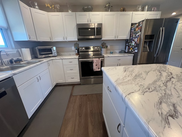 kitchen featuring a toaster, dark wood-style floors, white cabinets, stainless steel appliances, and a sink