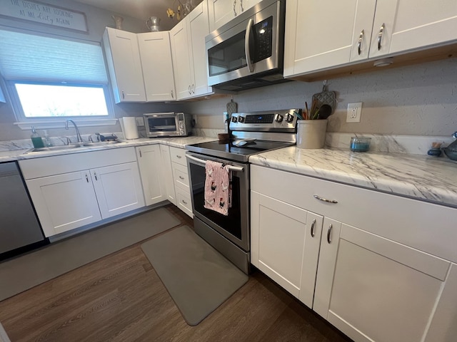 kitchen with dark wood finished floors, a toaster, a sink, white cabinets, and appliances with stainless steel finishes