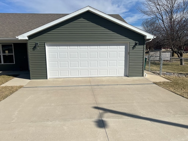 garage featuring concrete driveway and fence