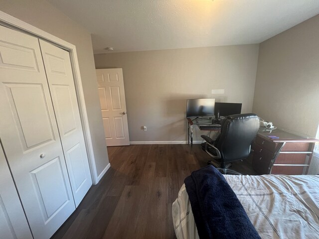 bedroom with wood finished floors, baseboards, and a closet