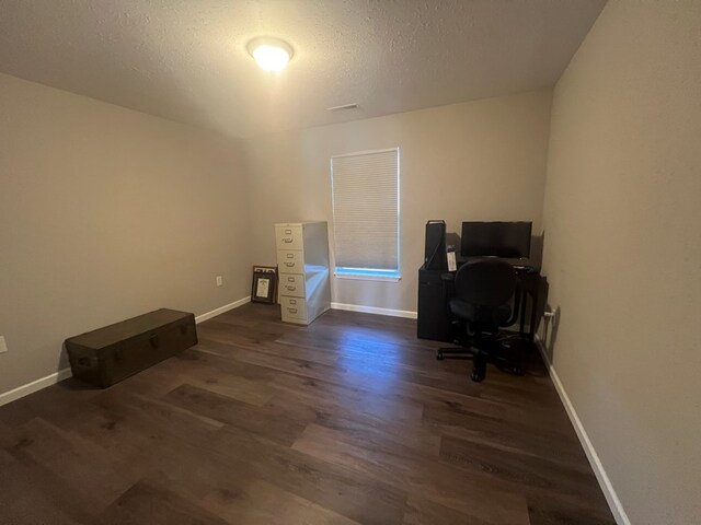 home office with visible vents, a textured ceiling, baseboards, and wood finished floors