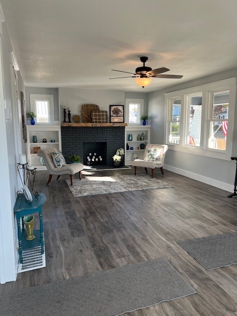 unfurnished living room with ceiling fan, dark wood-type flooring, and a brick fireplace