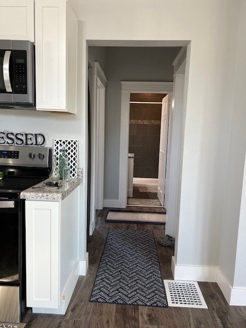 kitchen featuring white cabinets, stainless steel appliances, and dark wood-type flooring